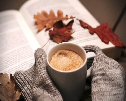 Person relaxing with a book and coffee by the window